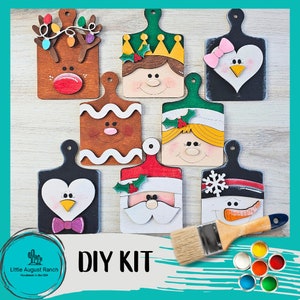 May include: DIY kit with seven wooden ornaments shaped like cutting boards, featuring various Christmas characters like Santa, a snowman, a penguin, a gingerbread person, and an elf. The kit includes paint and a brush.
