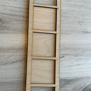 May include: A wooden shelf unit with three rectangular spaces. The shelf unit is made of natural wood and has a rustic look.