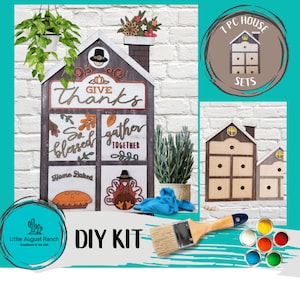 May include: DIY kit for a wooden house shaped Thanksgiving sign. The sign has four windows with Thanksgiving-themed images and text, including "Give Thanks", "So Blessed", "Gather Together", and "Home Baked". The kit includes paint and a paintbrush.