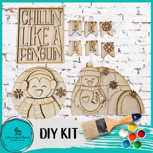 May include: DIY craft kit featuring a penguin and an igloo. The kit includes wooden cutouts, paint, and a paintbrush. The wooden cutouts are unpainted and ready to be decorated. The kit also includes a sign that says "Chillin Like A Penguin".