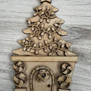 May include: A wooden Christmas tree ornament with a door and candy cane decorations. The tree is decorated with lights and a star on top.