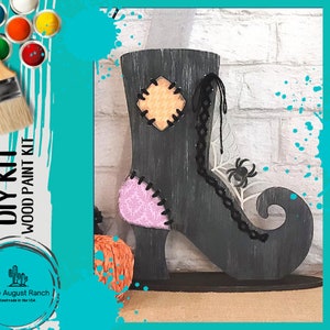 May include: DIY wood paint kit featuring a witch's boot with a black, gray, and white color scheme. The boot has a spider web design and a spider on the side. The kit includes paint and instructions for painting the boot.