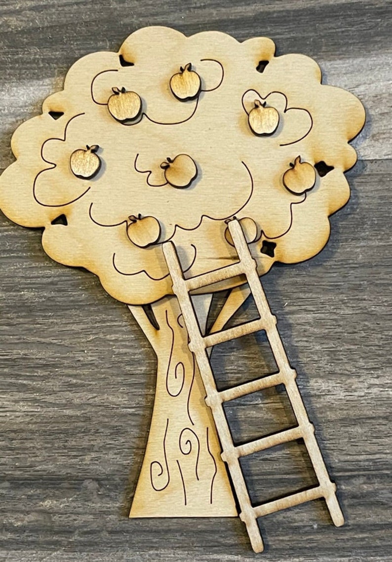May include: A wooden apple tree with a ladder. The tree has seven apples on it. The tree and ladder are both unfinished and ready to be painted.