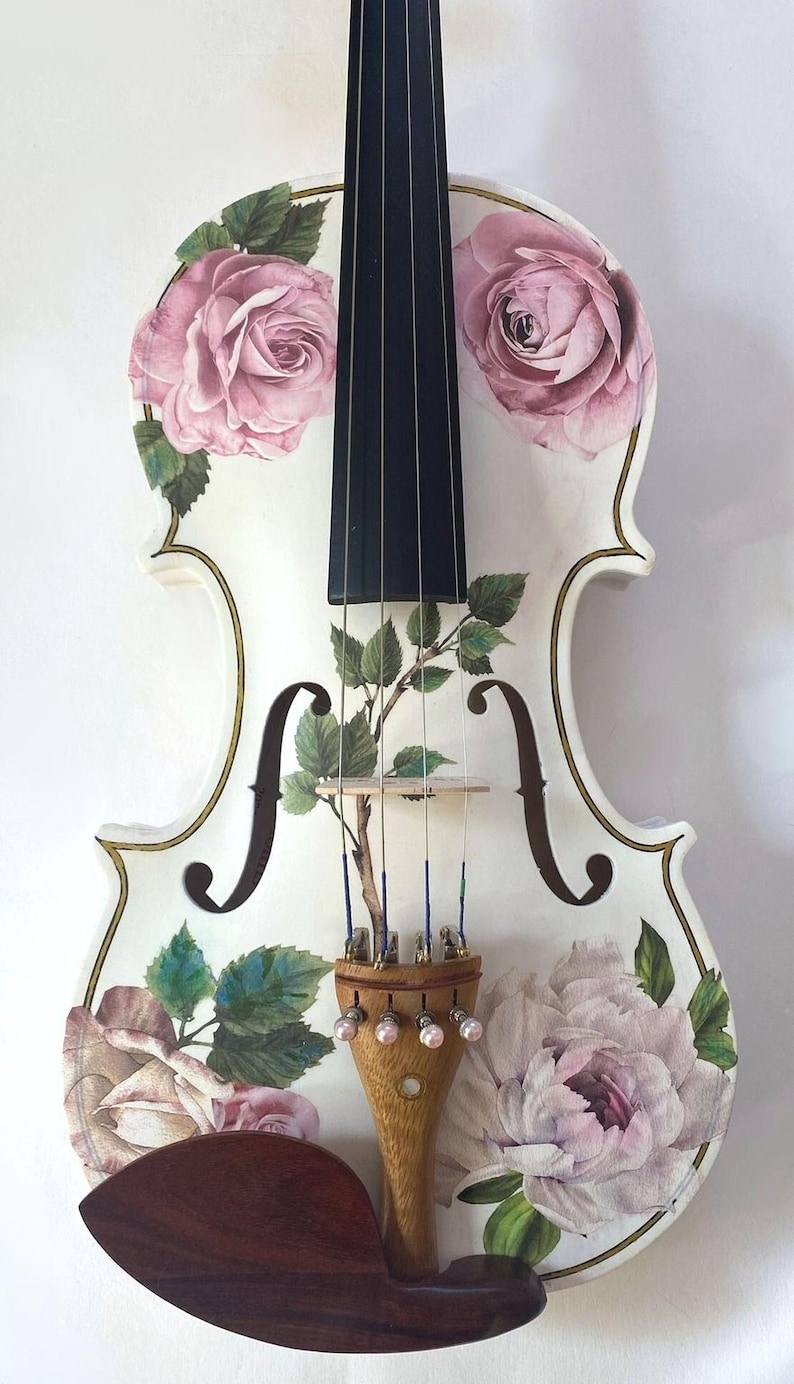 A white violin with a floral design on the body and a black neck, featuring pink roses and green leaves.