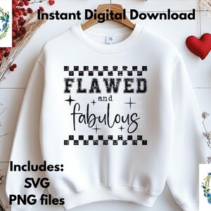 Op de afbeelding: Witte sweatshirt met de zwarte tekst "FLAWED and fabulous". Het ontwerp bevat een dambordpatroon en steraccenten. De tekst "Instant Digital Download" en "Includes: SVG PNG files" is ook zichtbaar.
