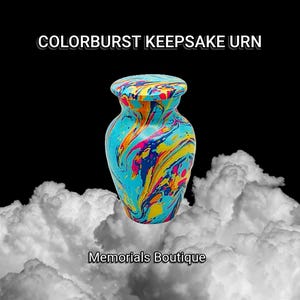 May include: A small, colourful keepsake urn with a swirling blue, yellow, pink and red marbled design. The urn is sitting on a white cloud-like background. The text "COLORBURST KEEPSAKE URN" is at the top of the image and the text "Memorials Boutique" is at the bottom of the image.