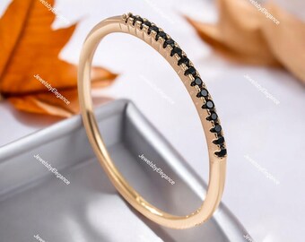 May include: A delicate gold band ring with a row of small black gemstones. The ring is simple and elegant, perfect for everyday wear.