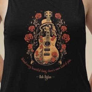 May include: Black tank top with a graphic of a skull playing a guitar with red roses. The text "Behind every beautiful thing, there's some kind of pain. -- Bob Dylan --" is printed below the graphic.