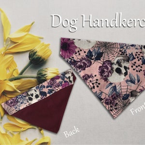 Könnte beinhalten: Ein rosa Hundehalstuch mit einem floralen und Totenkopf-Muster auf der Vorderseite und einer einfarbigen burgunderroten Farbe auf der Rückseite. Das Halstuch ist mit "Dog Handkerchief" und "Front" und "Back" beschriftet.