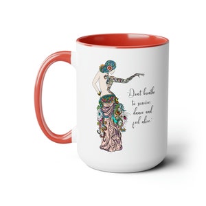 May include: White ceramic mug with a red rim and handle. The mug features a colorful illustration of a woman in a flowing skirt and the text "Don't breathe to survive: dance and feel alive."