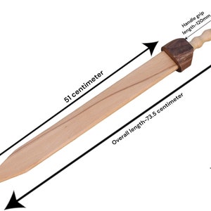 K&ouml;nnte beinhalten: Ein Holzschwert mit einem braunen Griff und einem runden Knauf am Ende. Das Schwert ist 51 Zentimeter lang und die Gesamtl&auml;nge betr&auml;gt 73,5 Zentimeter. Das Schwert wiegt 0,446 Kilogramm.