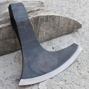 Peut inclure: Une hache à main noire avec une lame incurvée et un manche en bois. La hache repose sur un morceau de bois.