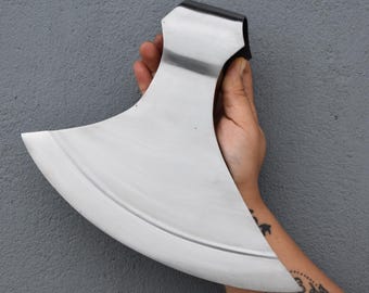 May include: A large, polished steel axe head with a curved blade. The axe has a black handle and a wide, crescent-shaped blade. The axe is held against a gray background.