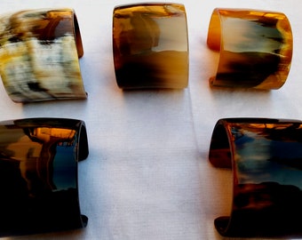May include: Five horn bracelets in a variety of colours and patterns. The bracelets are made from polished horn and have a smooth, glossy finish. The bracelets are all different sizes and shapes, but they are all made from the same material.