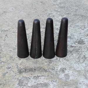 May include: Four black wooden bowling pins arranged in a row on a gray concrete surface.