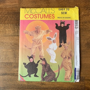 May include: A vintage McCall's Costumes pattern envelope showing illustrations of animal costumes such as a lion, bear, bunny, and cat. The envelope is yellow with red and pink accents and includes the text "EASY TO SEW".