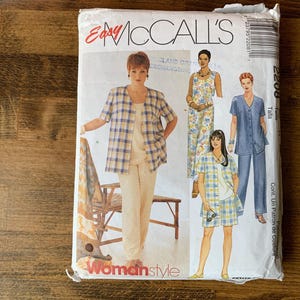 May include: An Easy McCall's sewing pattern envelope, number 2208, featuring illustrations of various outfits including a plaid jacket, solid pants, a floral jumpsuit, and a plaid shorts set. The white paper envelope displays the brand name and style.