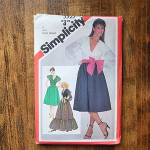 May include: Simplicity sewing pattern number 5927 for a skirt and blouse. The pattern is for misses sizes 12-16. The pattern shows three different styles of skirts and blouses. The model is wearing a white blouse with a ruffle collar and a navy blue skirt with a pink bow.