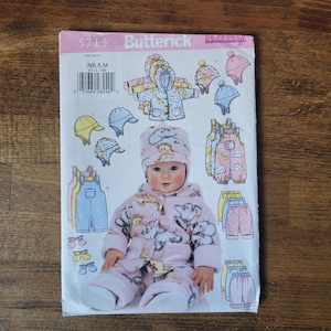 May include: A sewing pattern for a baby's outfit, featuring a pink and white hooded jacket with animal print, a pair of blue dungarees, and a yellow and white hat. The pattern is from Butterick and is for sizes NB, S, and M.