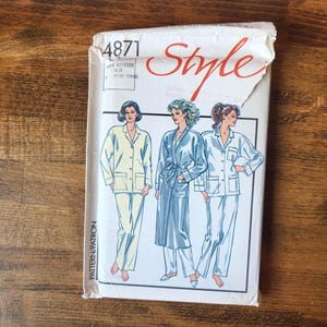May include: A white paper sewing pattern envelope labelled Style 4871. The front features illustrations of three individuals wearing pyjamas and a robe. The text includes the number 4871, the brand name Style, and the word PATRON printed vertically.