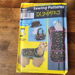 May include: A sewing pattern for a dog coat, dog hat, and dog apron. The pattern is titled "Sewing Patterns for Dummies" and is from Simplicity. The pattern includes a black and white illustration of a dog wearing the coat and hat.