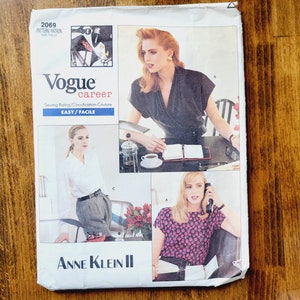May include: Vogue career sewing pattern envelope featuring three models wearing different outfits. The pattern is for a blouse, a top, and a pair of pants. The envelope is white with black text and a black and white photo of a model wearing a black blouse. The text on the envelope reads "Vogue career" and "Anne Klein II".