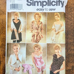 May include: A sewing pattern for a robe, top, and pyjamas. The pattern is from Simplicity and includes instructions for sizes M, L, and XL. The pattern shows a woman wearing a robe, a top, and pyjamas.