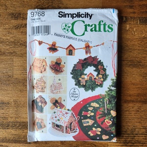 Puede incluir: Patrón de manualidades Simplicity Crafts 9768 para una casa de jengibre, una corona y una falda de árbol. El patrón es de Fanny's Fabrics en Calgary.