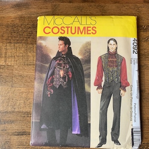 May include: McCall's Costumes pattern featuring a gothic vampire costume. The pattern includes a long black cape with a purple lining, a ruffled shirt, and a vest. The image also shows a second costume with a red shirt and vest.