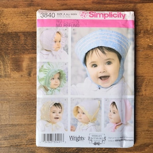 May include: A Simplicity sewing pattern envelope 3840 for infant bonnets. The cover features five photographs of infants wearing various styles of bonnets in white, green, blue, yellow, and pink. The text includes Simplicity, 3840, and Wrights.