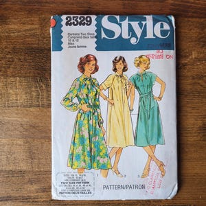 May include: A vintage sewing pattern for a dress, featuring three women wearing different styles of dresses. The pattern is labelled "Style" and "2329". The pattern includes two sizes, 10 and 12, and is for misses and young women.