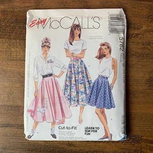 May include: A vintage McCall's sewing pattern envelope featuring illustrations of three women in skirts and tops. The envelope is white with text and the number 5782. The words "Cut-to-Fit" and "Learn to Sew for Fun" are also visible.