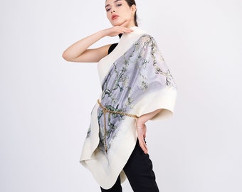 May include: A white and gray patterned scarf with a floral design. The scarf is draped over a person's shoulder and tied at the waist with a gold chain.