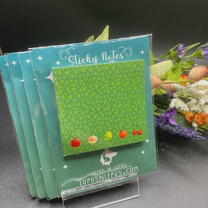 May include: A stack of sticky notes with a green triangle pattern and fruit illustrations. The top note has the words "Sticky Notes" in cursive. The bottom of the packaging has the text "Lupus N Lepus" and "lupusnlepus.com".