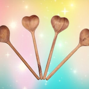 May include: Four wooden spoons shaped like hearts. The spoons are brown and have a natural wood finish.