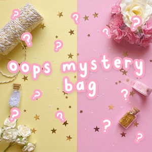 May include: A pink and yellow background with gold stars and question marks. The text "oops mystery bag" is written in pink letters.