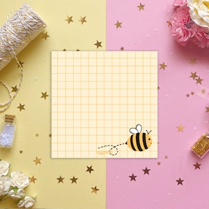 May include: A yellow and black bee on a white background. The bee is flying and has a dotted line behind it. The background is a grid pattern.