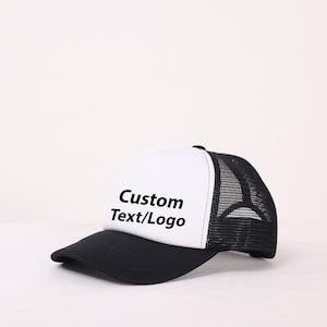 May include: A black and white trucker hat with a mesh back. The front of the hat is white and has the text "Custom Text/Logo" in black.