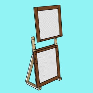 Può includere: Una cornice in legno con una rete bianca a maglia, montata su un cavalletto in legno. La cornice è marrone e il cavalletto è in legno naturale.