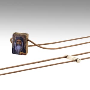 May include: A brown wooden pendant featuring a religious image of a bearded man in a white robe. The pendant is attached to a brown cord with a silver clasp.