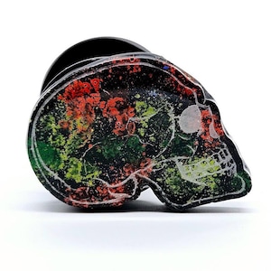 May include: Black skull-shaped planter with a colorful abstract design in shades of red, green, and yellow.