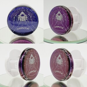 May include: Two phone grips with a purple and blue design. The design features a white triangle with a circle inside and the word "ORACLE" written below.