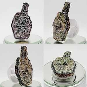 May include: Four different views of a black and gold glitter cupcake phone charm. The cupcake has a single candle on top and is attached to a white phone ring.