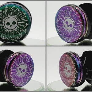 May include: A pair of black and iridescent ear gauges featuring a white skull and sunflower design. The gauges are shown from different angles.