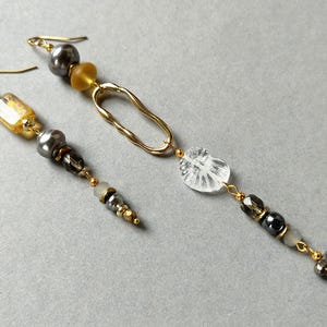 Longues boucles d'oreillesペンダントdépareillées en perles de cristal boho。ボエームな前衛的なスタイル。ビジュー・ド・デクラレーション。