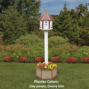 May include: A white birdhouse with a red roof and three nesting compartments sits atop a white post. The post is attached to a hexagonal planter with brown panels and red trim. The planter is filled with red and yellow flowers. The planter colors are: Clay panels, Cherry trim.
