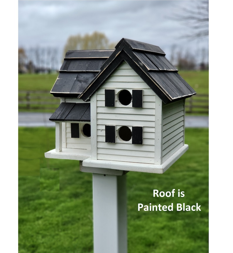 May include: A white birdhouse with a black roof and black shutters. The birdhouse has two nesting compartments and is mounted on a white pole. Roof is Painted Black.