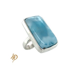 May include: A silver ring with a large, rectangular, light blue gemstone. The gemstone has a cloudy, marbled pattern.