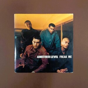 Op de afbeelding: Albumhoes met vier mannen in overhemden. De tekst "ANOTHER LEVEL FREAK ME" is zichtbaar. De achtergrond heeft een warme, oranje tint. De mannen kijken naar de camera.