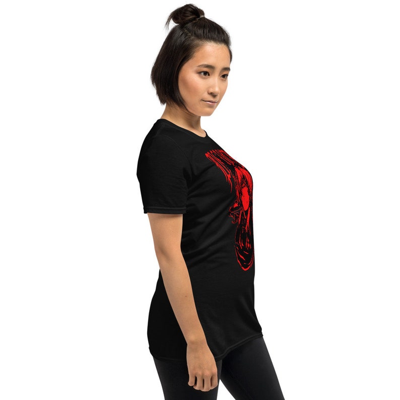 May include: A black t-shirt with a red graphic print of a woman's face. The graphic is stylized and abstract.